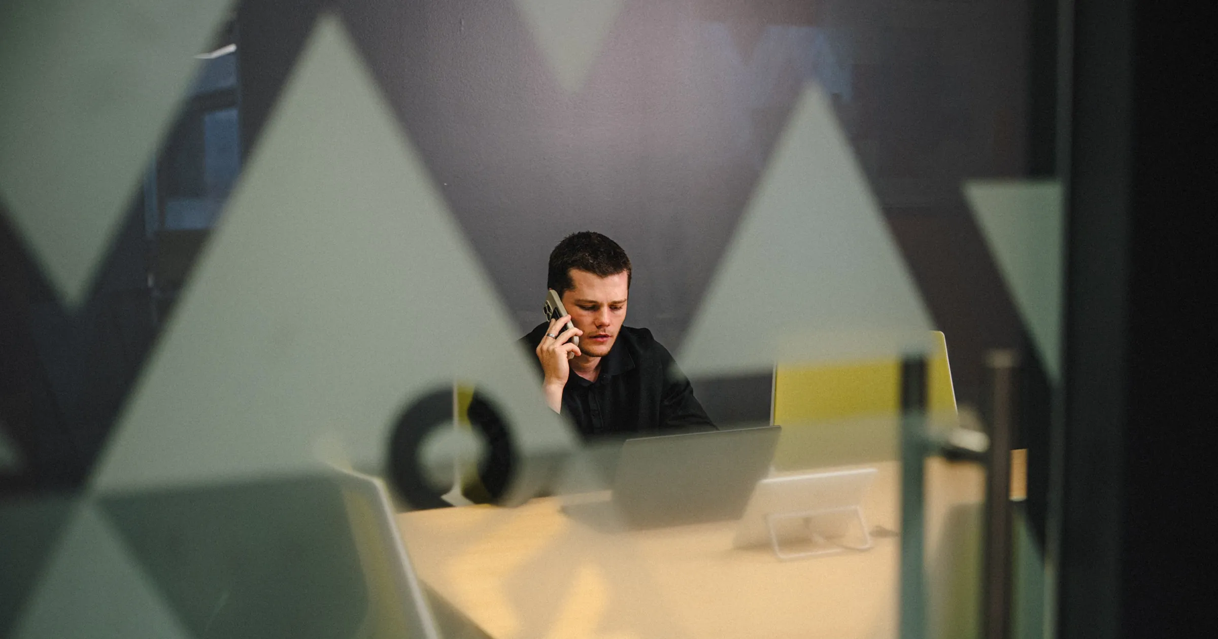 IT director on a phone call at a conference table, reviewing compliance obligations now that CMMC Phase 2 suspended its third-party assessment requirement