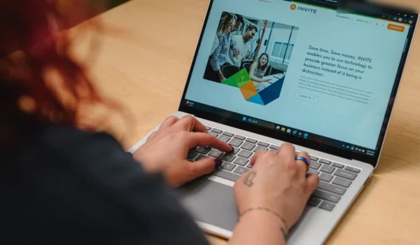 INVITE employee reviewing the INVITE Networks managed services page on a laptop while planning an enterprise AI strategy