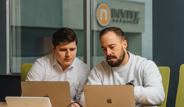 Two INVITE engineers review recovery plans together on laptops in a conference room