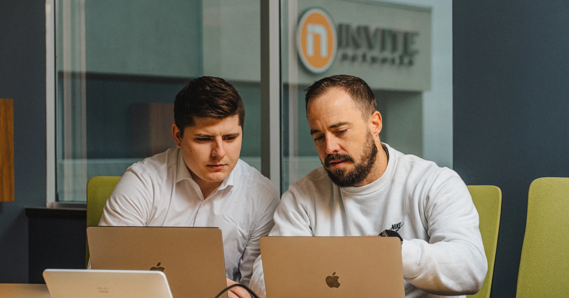 Two INVITE engineers review recovery plans together on laptops in a conference room